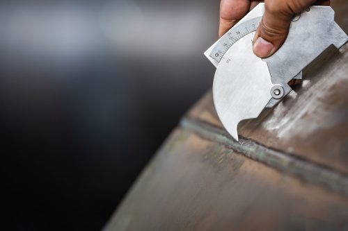 QC Technician inspector using welding gauge inspection butted weld on plate steel structure in industry fabrication factory. NDT